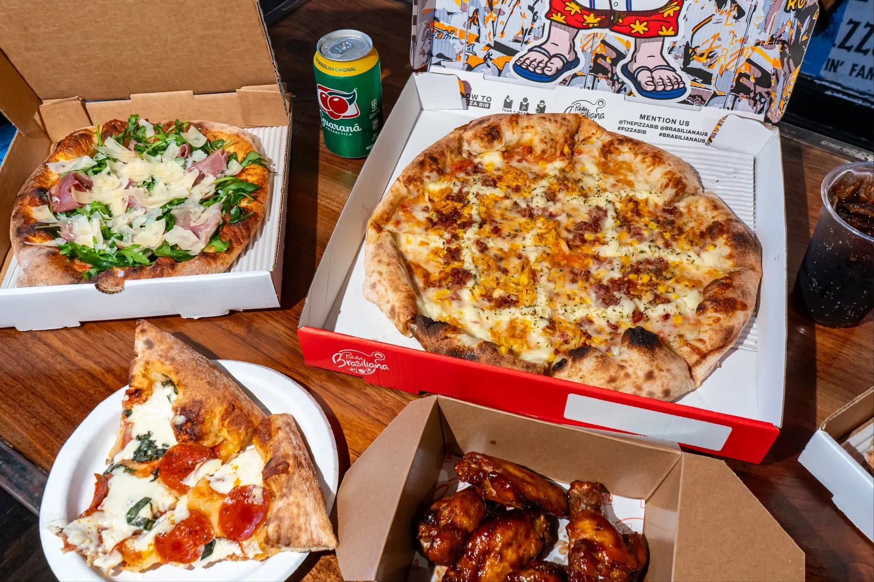 A spread of Brasiliana pizzas fresh from the oven, boxed and ready to share